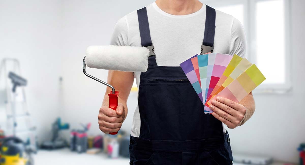 Artisan peintre tenant un rouleau et un nuancier de couleurs