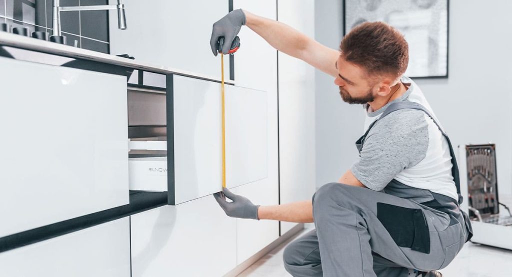 Prise de mesure par un cuisiniste pour l'installation d'une cuisine moderne
