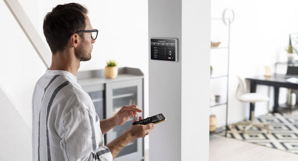 Homme utilisant des équipements domotiques indispensables pour piloter les fonctions de sa maison intelligente