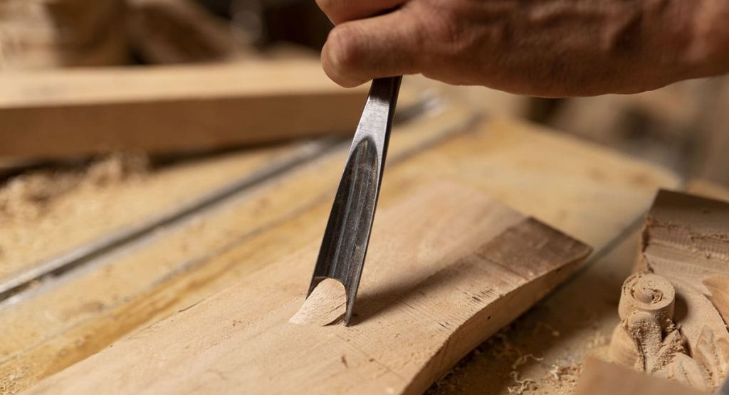 Technique de sculpture sur bois avec outil manuel, artisan en plein travail d’ébénisterie