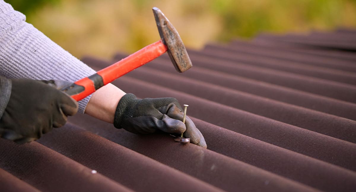 Couvreur installant une couverture en tôle ondulée sur un toit