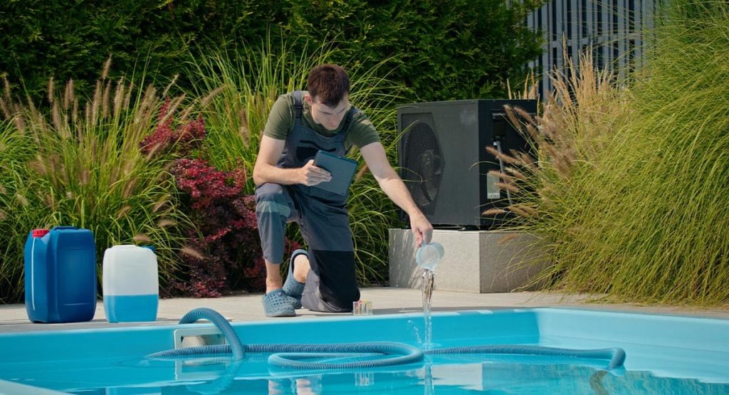 Pisciniste en train de contrôler l’eau d’une piscine avec des produits d’entretien
